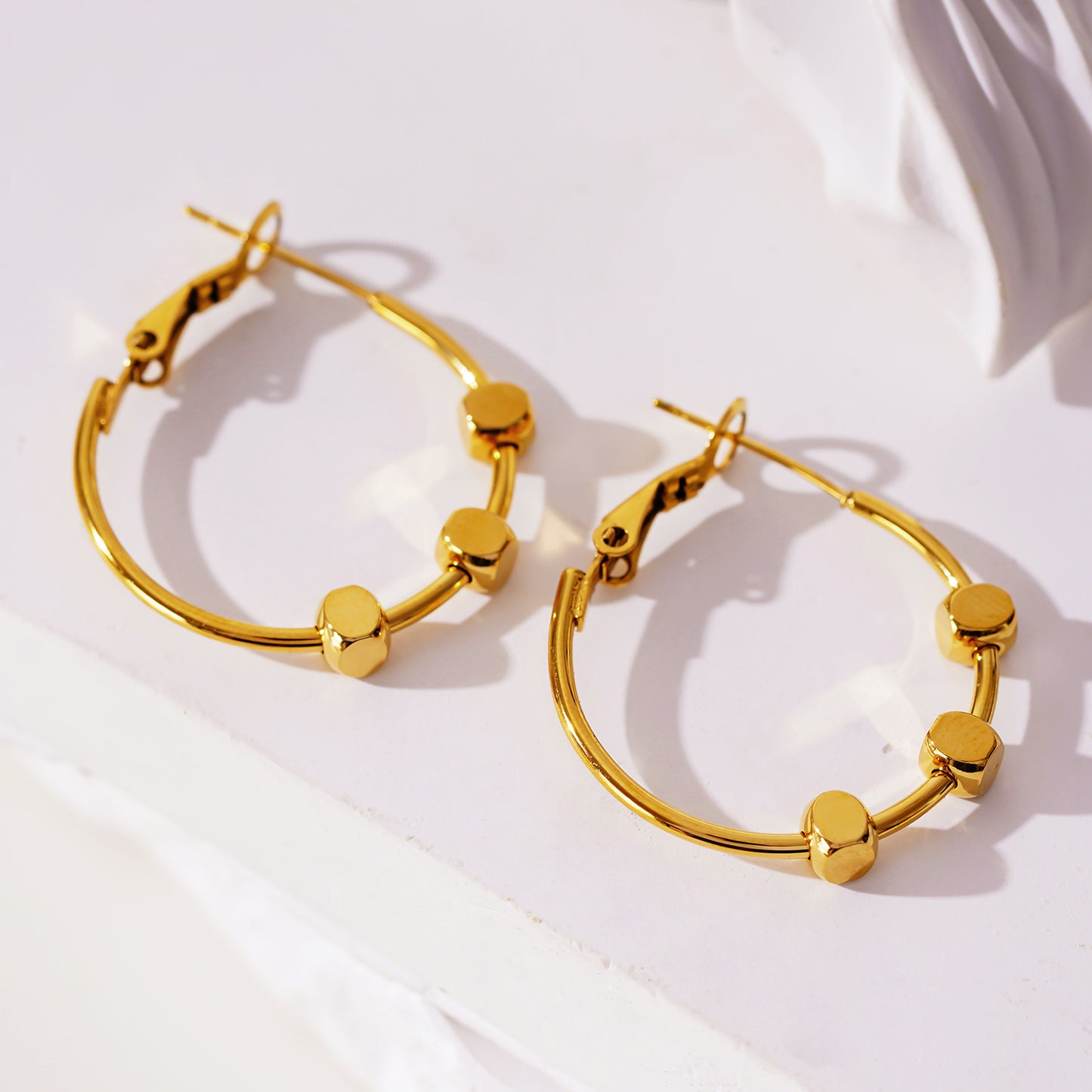 Style MASUYO 1079: Avant-Garde Rounded Hoop Earrings Anchoring a Trio of Square Beads.