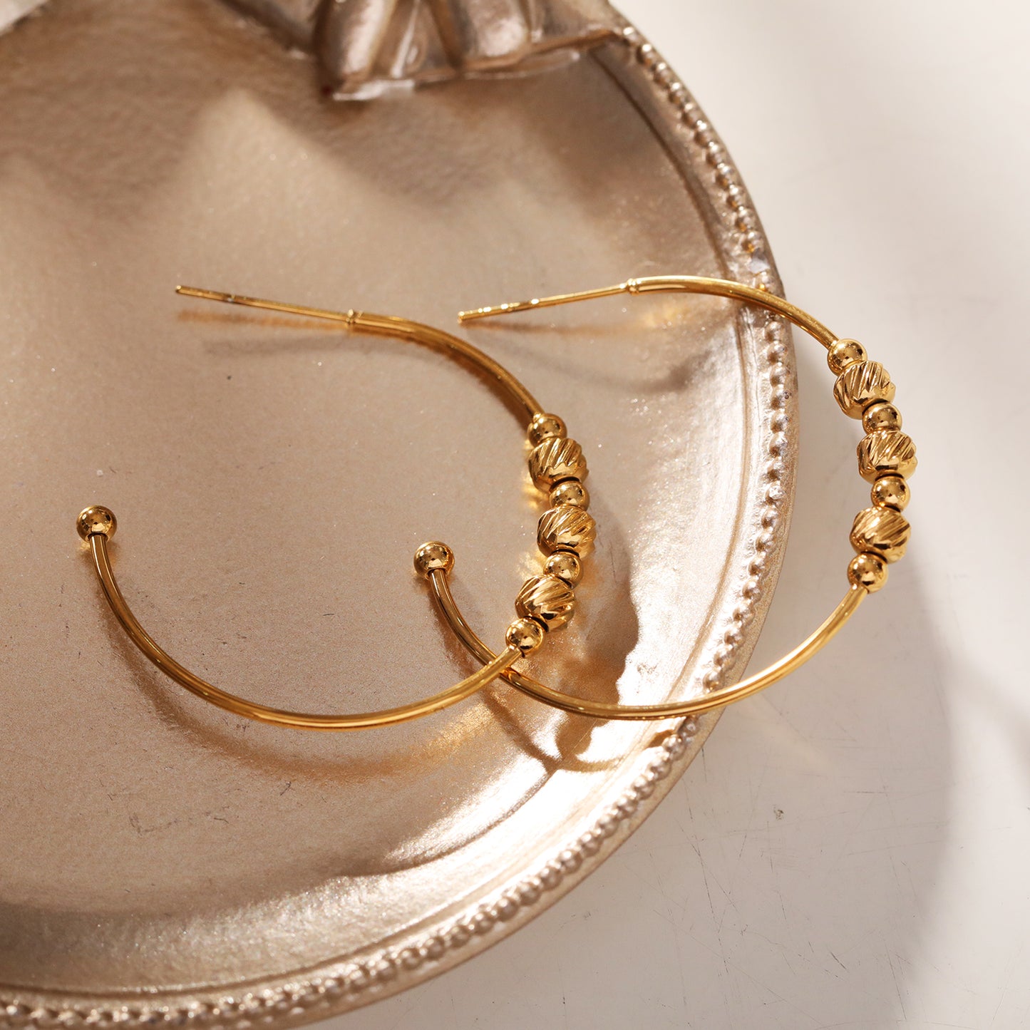 CHARIS: Classic Round Hoop Earrings Anchoring a Bevy of Charm Beads