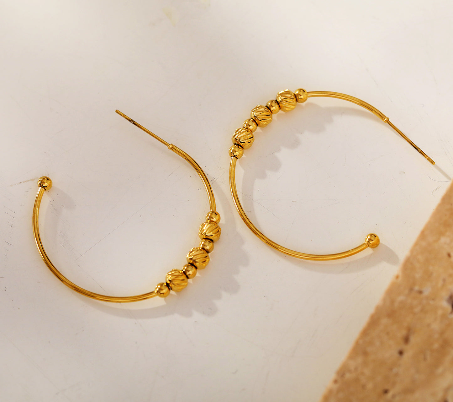 CHARIS: Classic Round Hoop Earrings Anchoring a Bevy of Charm Beads